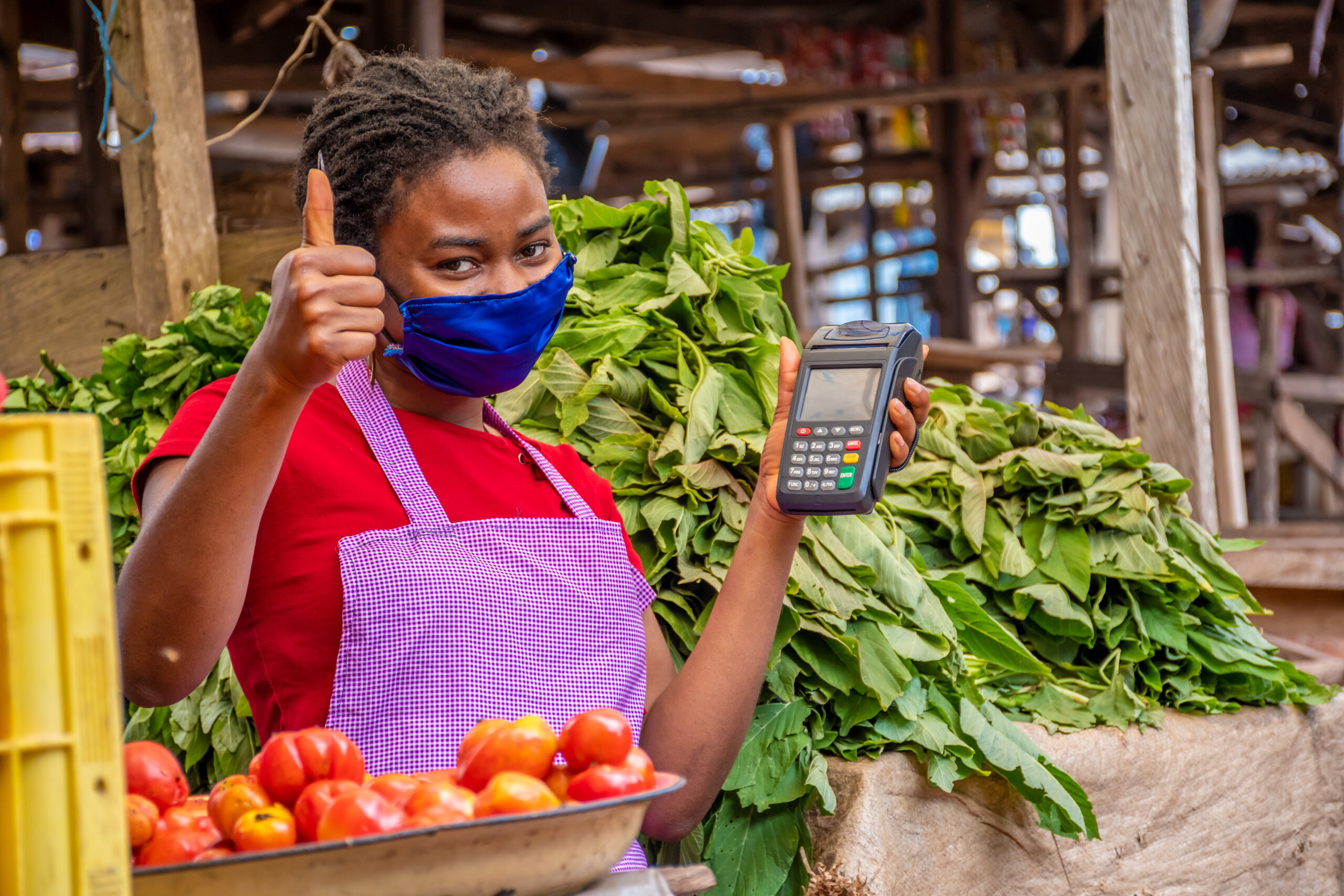 shallow focus woman with facemask holding pos machine market scaled.jpg